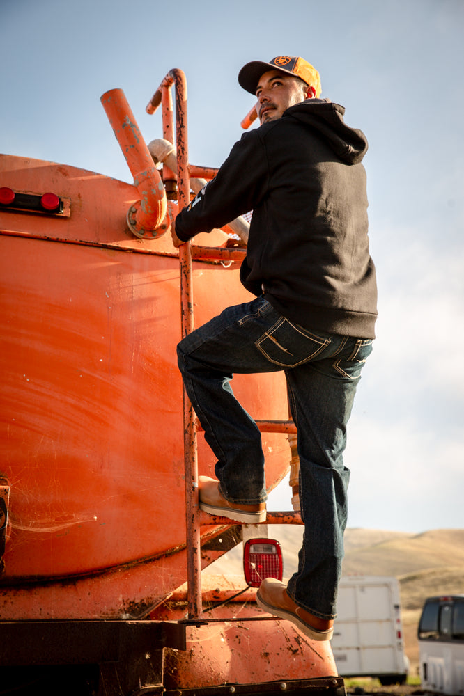 construction worker in casual clothing climbs on equipment at a construction site