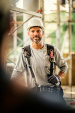 smiling construction worker in safety gear and hard hat at a construction site