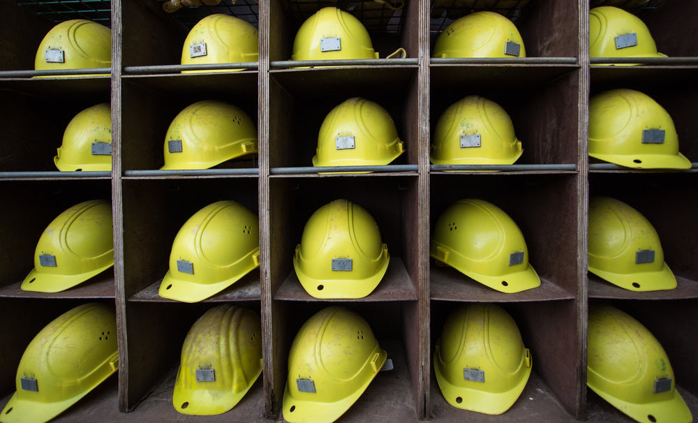 four rows of clean bright hard hats on shelves at a construction site