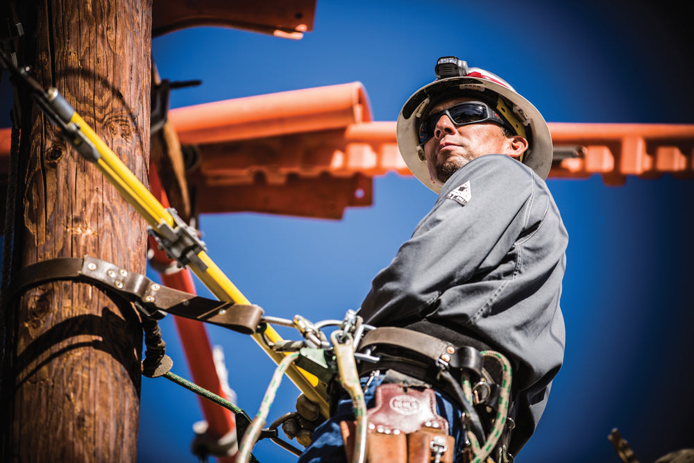 worker harnessed to a pole in full safety gear at a construction site 